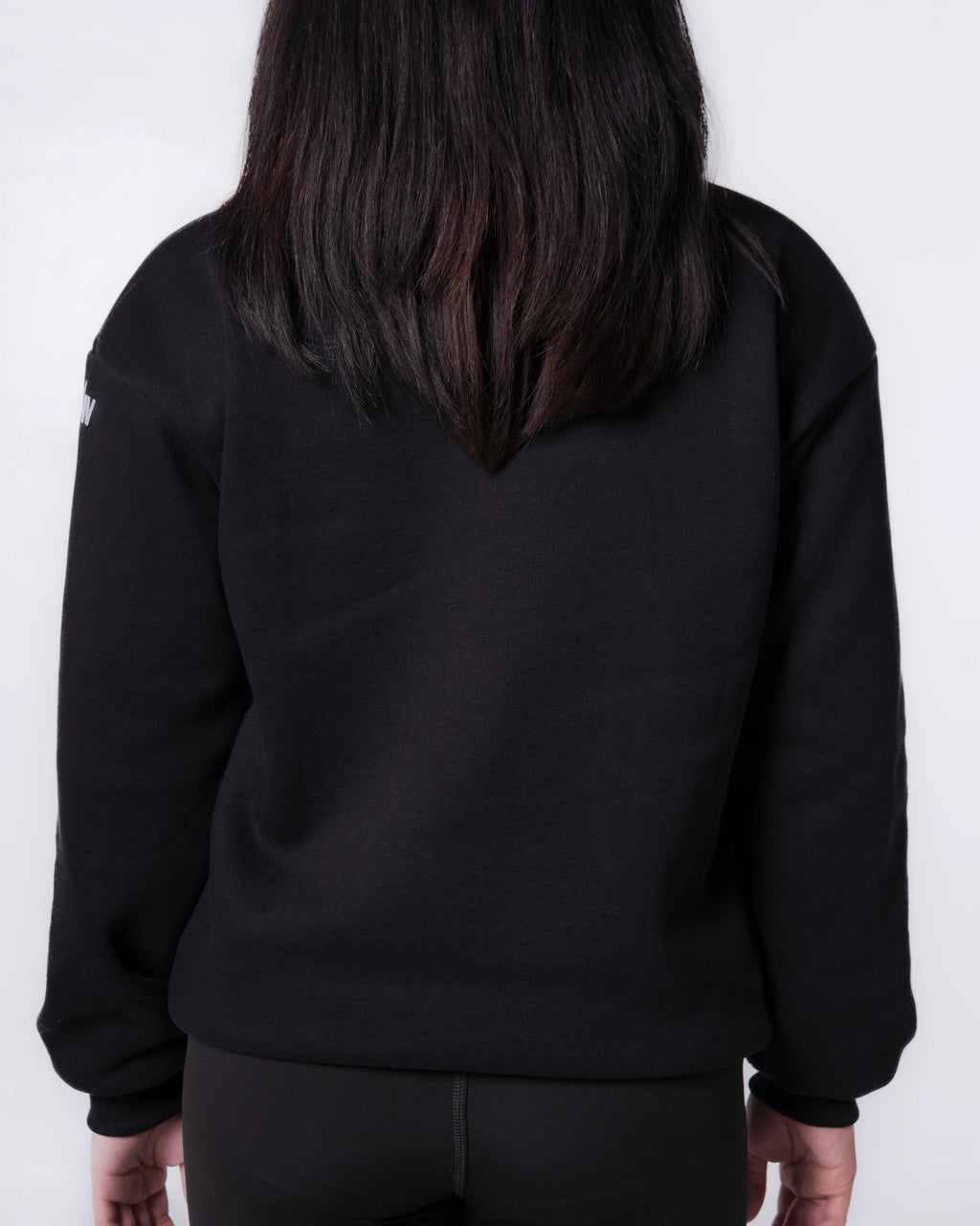 Person wearing a Black sweatshirt with a white logo on the back against a white background
#color_black